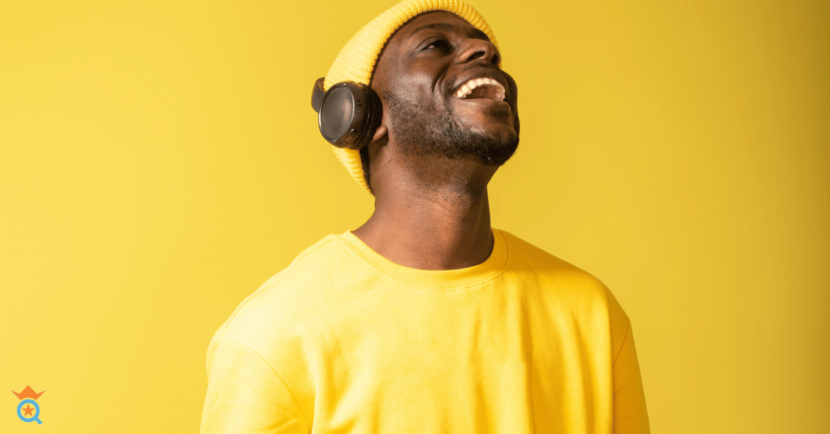 A guy smiling wearing a headphone in yellow shirt on a yellow background