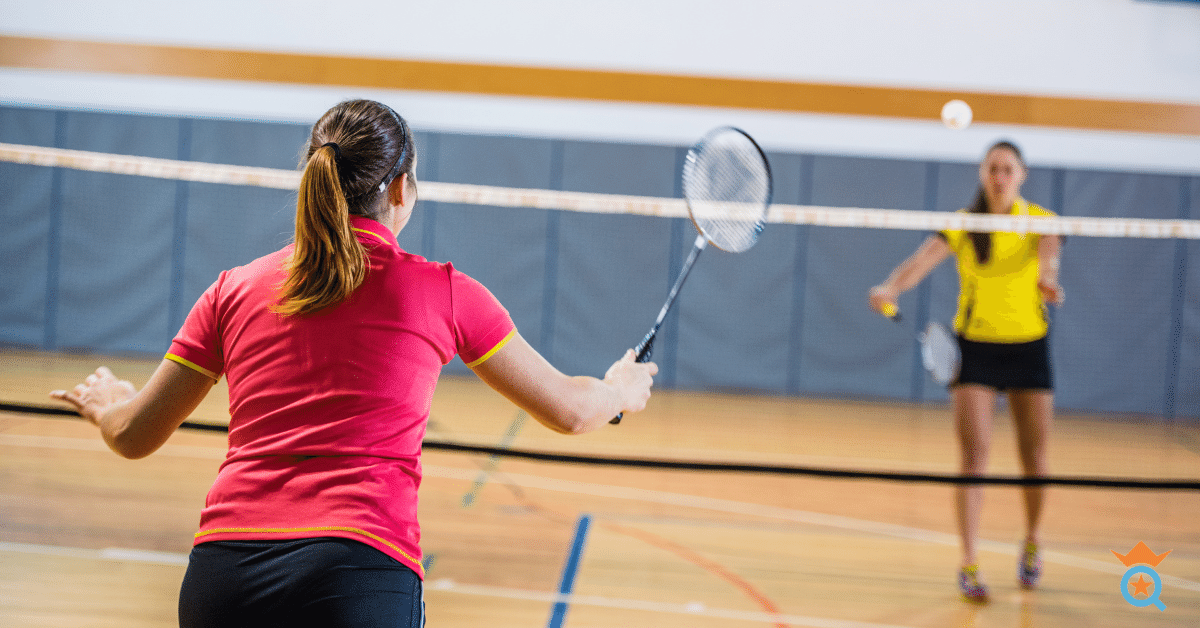two female players playing badminton inside a court